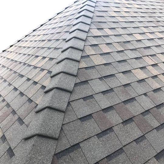Asphalt roof ridge cap shingles covering the peak where two sloping roof sections meet.