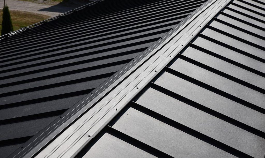 Metal roof ridge cap secured over the upper edges of standing seam roof panels.