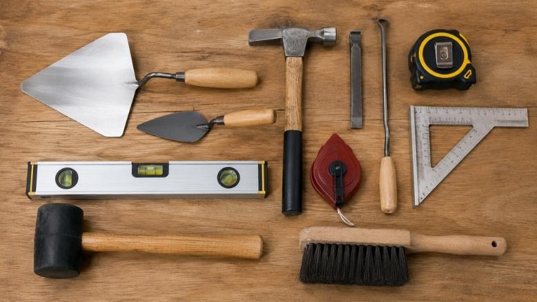 Essential masonry hand tools arranged on a workbench.