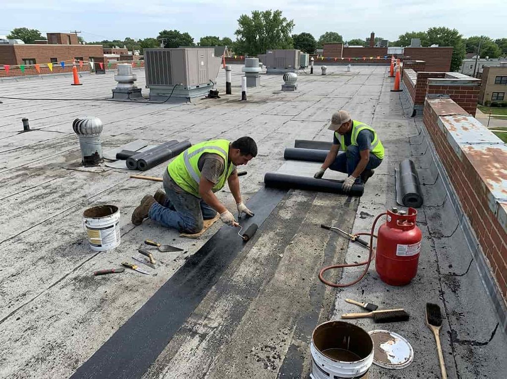 Technician applying a membrane patch to repair a leak on a flat roof 