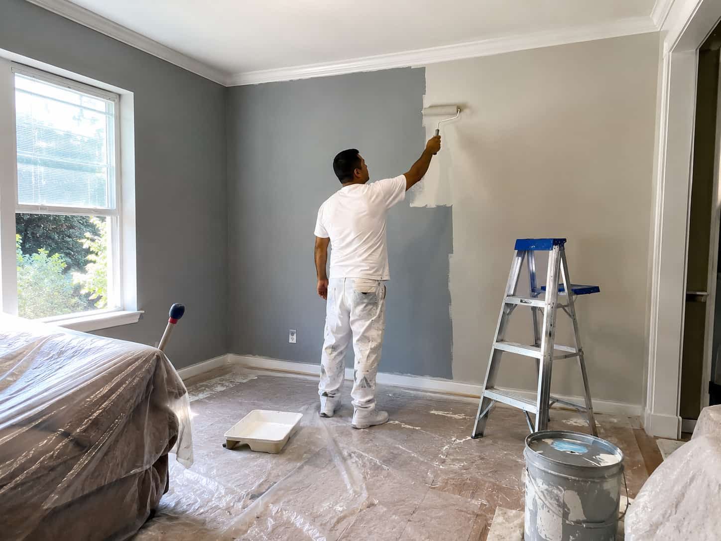 A Worker Painting The Interior Wall Of A House