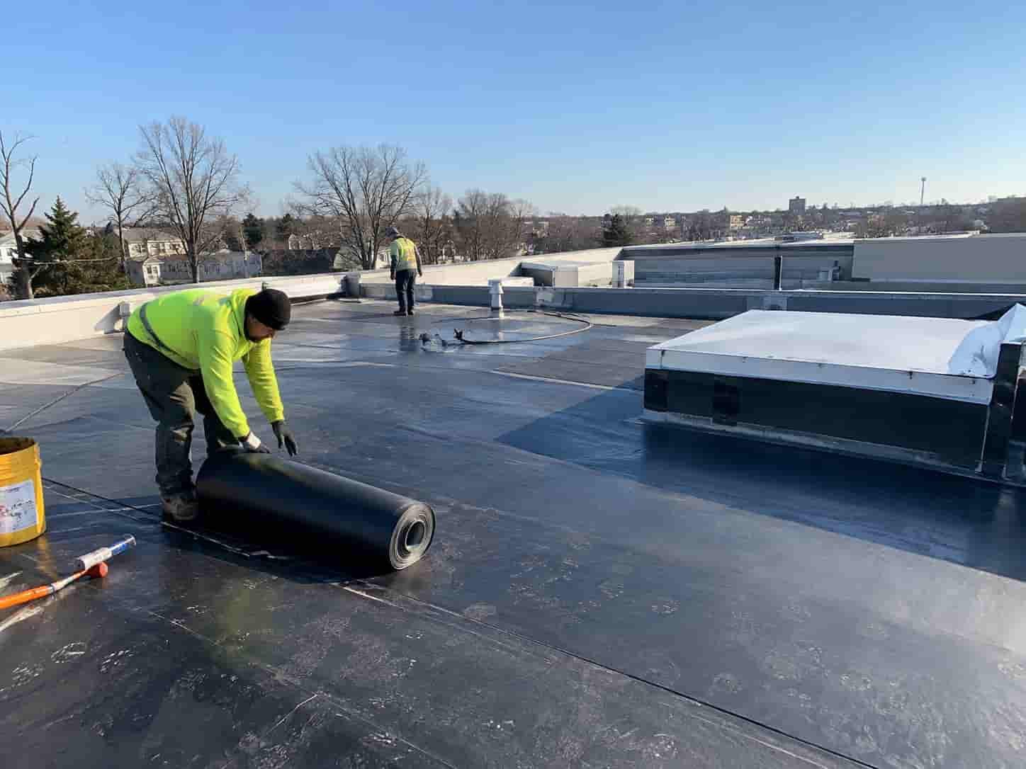 workers laying flat roof sheet on a roof in bethseda